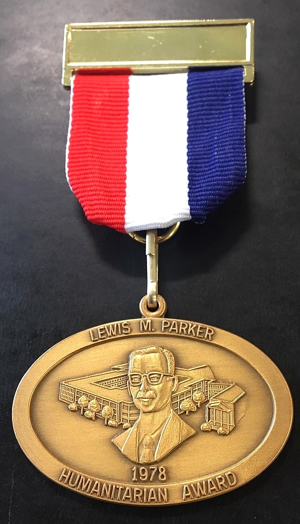 The Lewis M. Parker Humanitarian Award medal: an oval bronze medal bearing a relief portrait of Lewis M. Parker with the Masonic Home behind him and the date 1978, suspended from a red, white and blue ribbon.